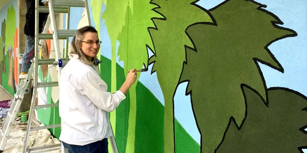 Bobbie Rae Jones paints a mural of green trees