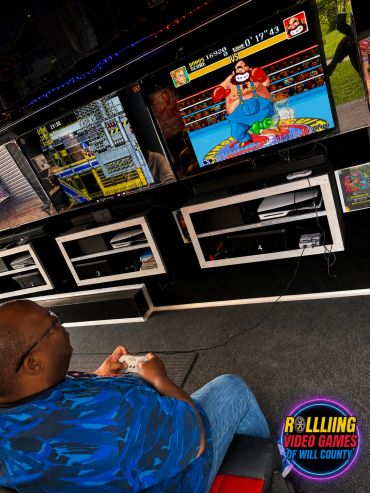Person playing a retro boxing video game on a large screen.