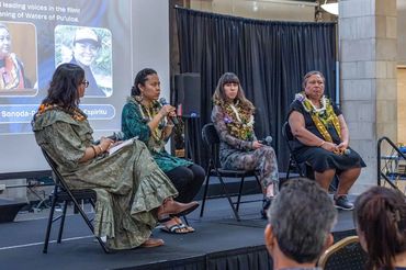 Panel discussion with four women on stage, engaging an audience.