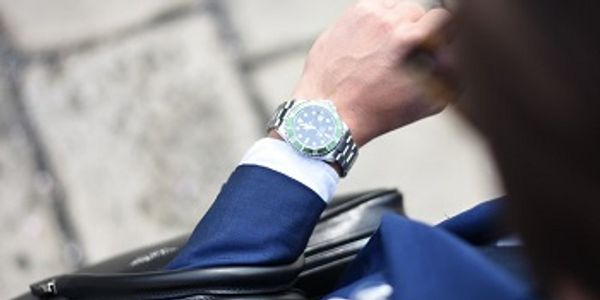 Person in suit checking time on a wristwatch outdoors.