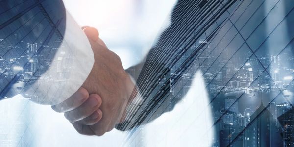 Two people shaking hands with a cityscape and modern buildings overlay.