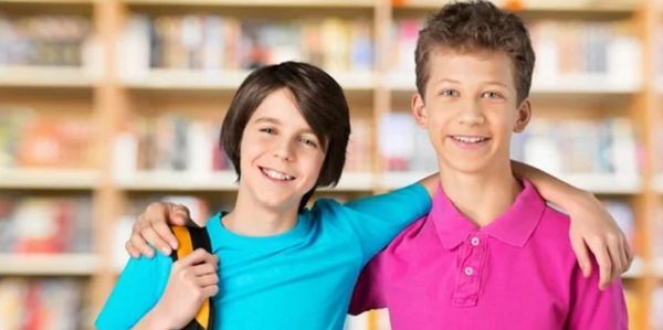 Two boys smiling with their arms around each other.