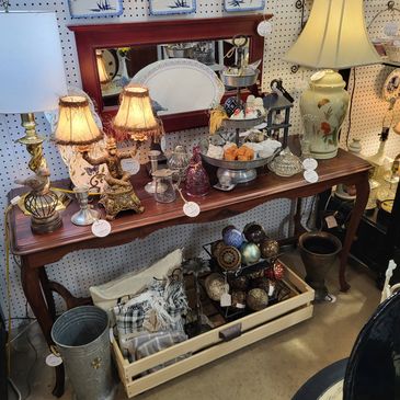 Vintage wooden table with decorative lamps and assorted home decor items.