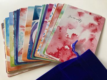 Colorful affirmation cards with positive messages and a blue velvet pouch.