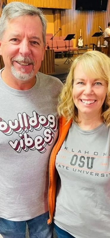 Smiling couple wearing university-themed shirts in a cozy indoor setting.