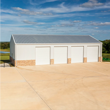 A large metal garage with four closed doors under a blue sky.