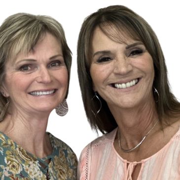 Two middle-aged women smiling warmly at the camera against a white background.