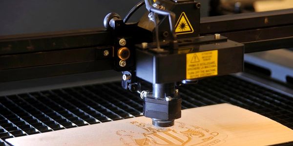 Laser engraving machine etching a design on wood.