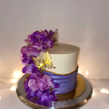Elegant cake decorated with purple flowers and golden butterflies.