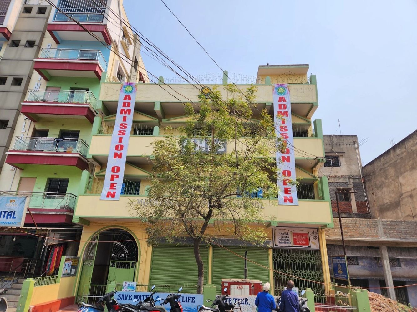 Multi-story building with admission open banners and parked motorcycles.