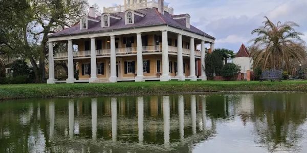 Historic mansion with columns by a reflective pond.