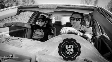 Two men wearing sunglasses sitting in an old car.