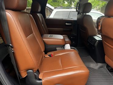 Interior of a vehicle with brown leather seats and center armrest.