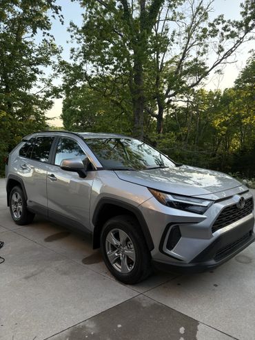 Silver SUV parked on a driveway surrounded by green trees.