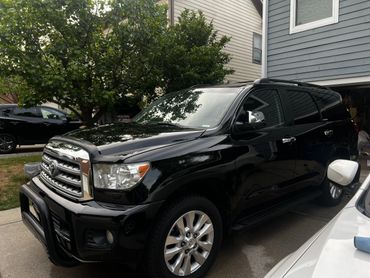 A shiny black Toyota SUV parked in a driveway beside a house.
