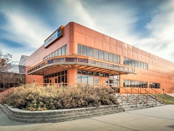 Modern building with a copper-toned facade and large windows under a partly cloudy sky.