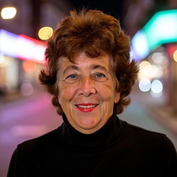 Smiling woman with curly hair in city night lights.