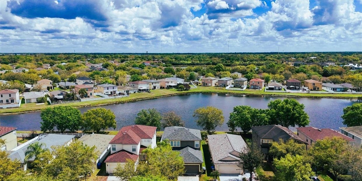 A suburban neighborhood with houses and a lake under a cloudy sky.