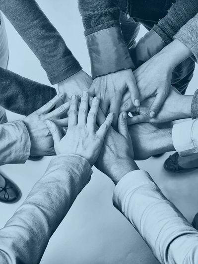 Photo of hands overlapping in a cheer in the middle of a circle of people