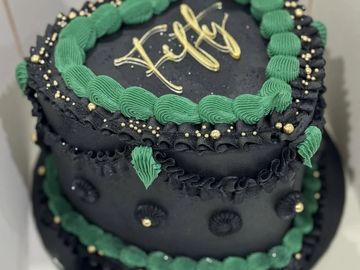 Black and green birthday cake with gold accents.