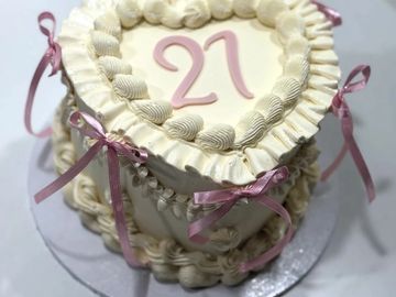 Heart-shaped 21st birthday cake with pink ribbons.