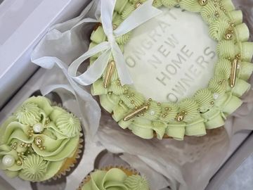 Green frosted cake and cupcakes congratulating new homeowners.