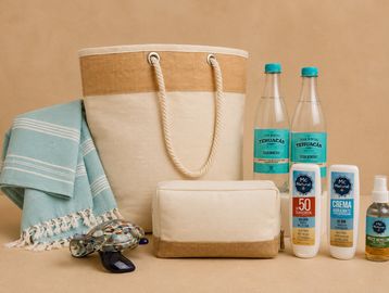 Beach essentials including a tote bag, towel, sunglasses, sunscreen, and water bottles.