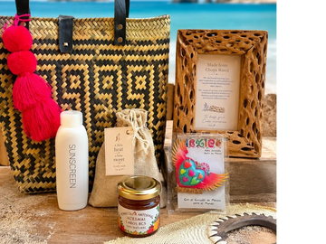 Beach essentials including sunscreen, woven bag, and natural products arranged with a sea backdrop.