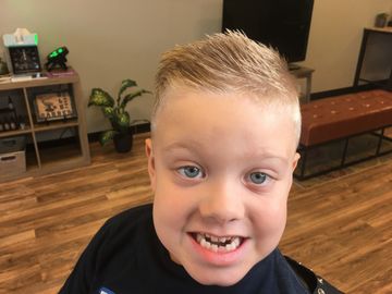 Smiling young boy with a fresh haircut in a cozy room.