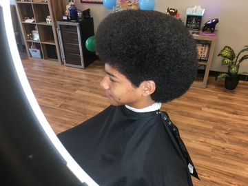 Young man with a large afro haircut in a barber's chair.