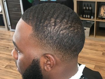 Man with a fresh wave haircut and neatly trimmed beard in a barbershop.