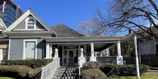 A charming nail spa in a renovated house with a welcoming porch and lion statues.