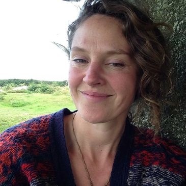 Woman smiling outdoors against a rock.