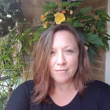 Woman with brown hair in front of a flowering plant.