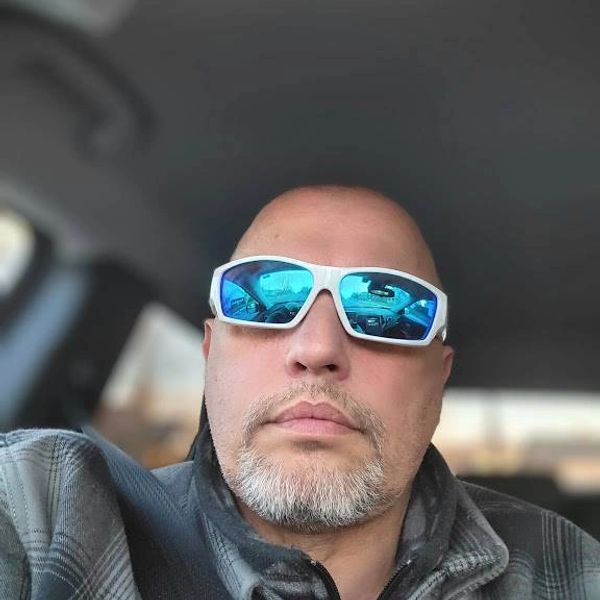 Man wearing reflective sunglasses inside a car.
