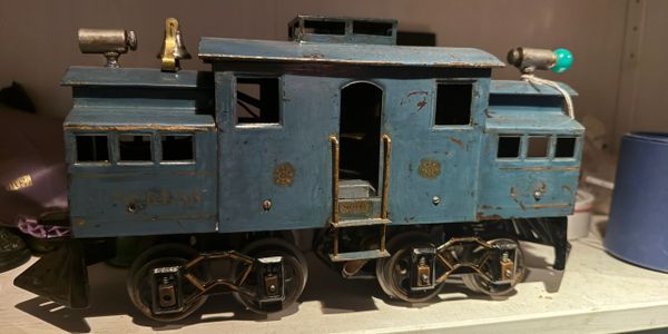 Vintage blue toy train engine with worn paint on a shelf.