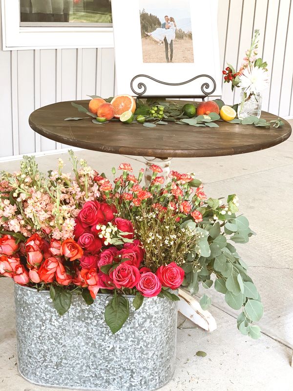 table with fruits and a container full of roses and leaves