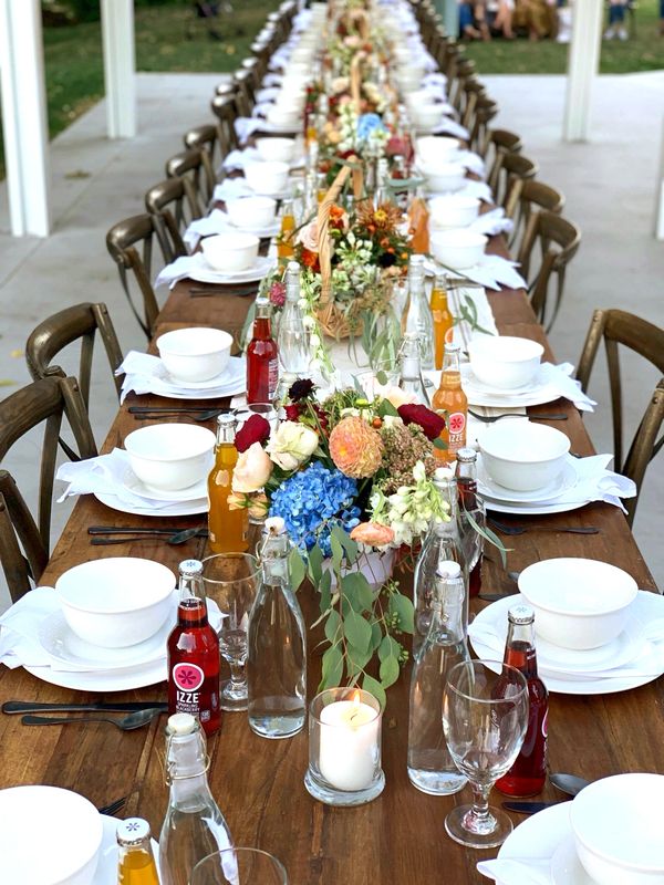 closeup wooden table with table settings bottles of pop and flower centerpieces