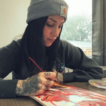 Woman painting with focus and tattoos.