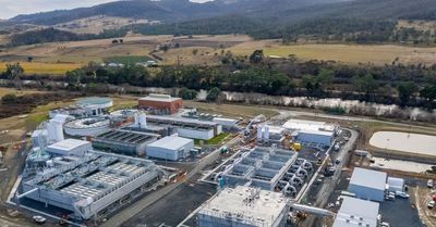 A large industrial plant surrounded by fields and hills.