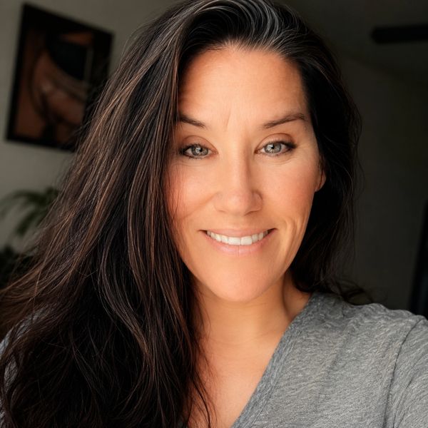 Smiling woman with long dark hair and gray eyes in a casual gray shirt.