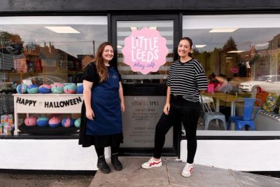 Two women standing outside a baby cafe with Halloween decorations.