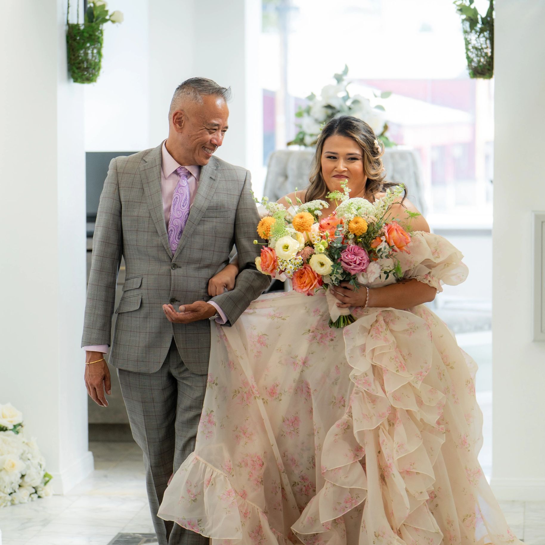 A bride holding a bouquet, walking with a smiling man in a suit.