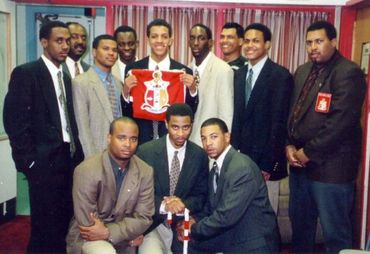 A group of men dressed in suits, one holding a red and white crest.