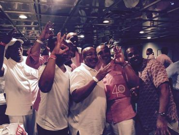 A group of men posing together with hand signs in a dimly lit room.
