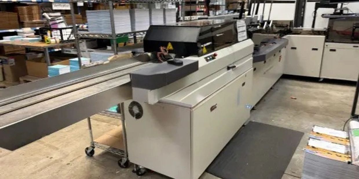 Large printing or binding machine in a warehouse.