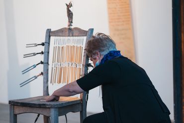 Woman interacting with a unique musical chair instrument with tuning forks.