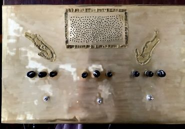 Vintage control panel with knobs and perforated speaker grille on a brass surface.