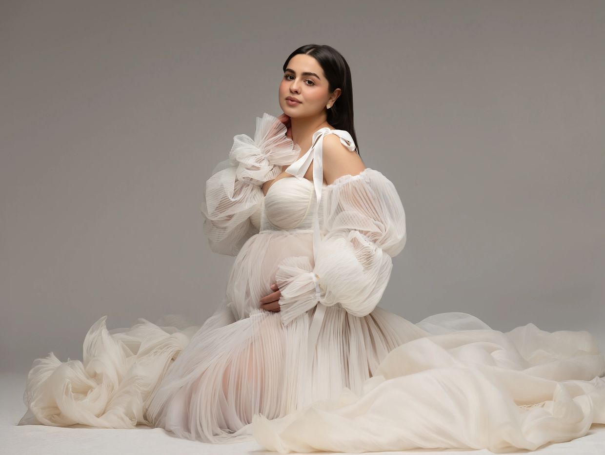 Pregnant woman in elegant white dress posing.