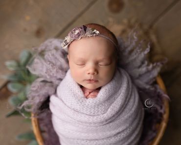 newborn girl wrapped in delicate lilac during her newborn session at chino hills photography studio.